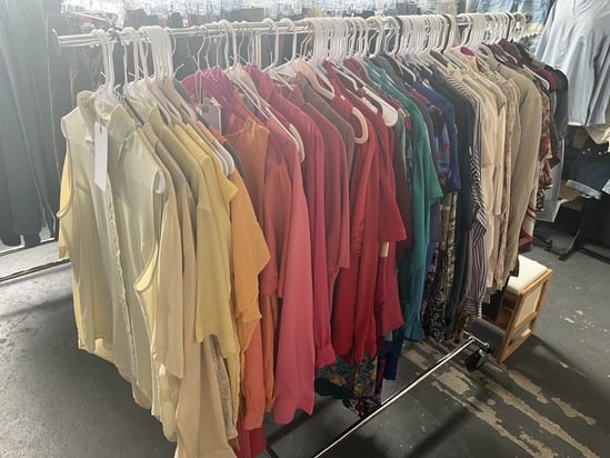 Rack of colorful vintage tops and blouses at Earthy Edits