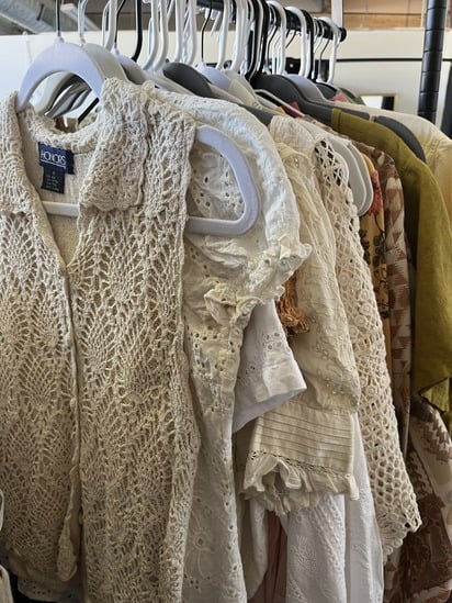 Rack of cream-colored lace and knit vintage clothing at Earthy Edits