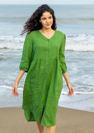 Woman wearing a green linen midi dress from Earthy Edits, standing on the beach